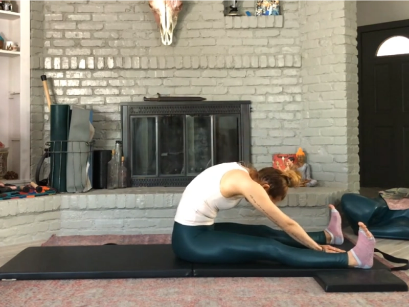 Perform the Spine Stretch Forward exercise on a mat.