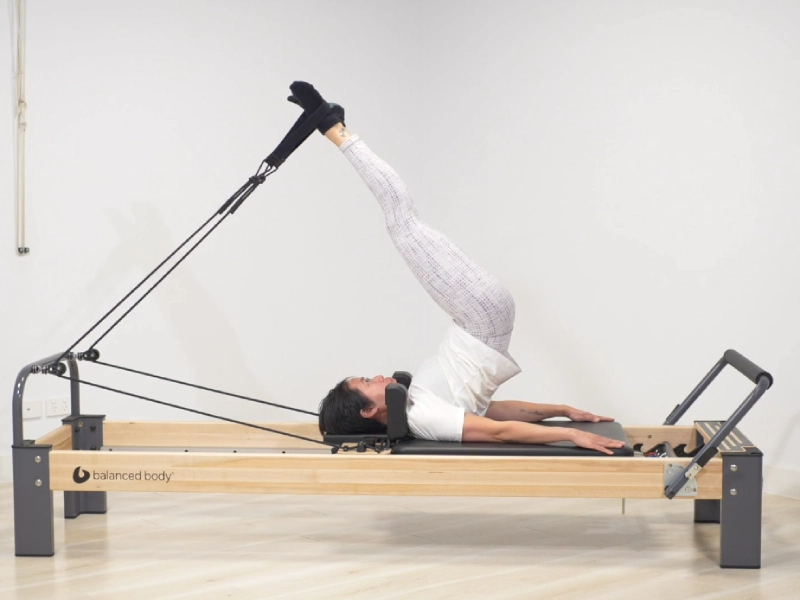 Steps to perform the Pilates Short Spine exercise on a Reformer.