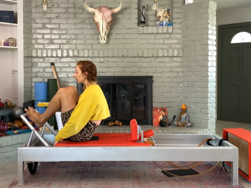 Steps to perform the Pilates Stomach Massage Round Back exercise on a Reformer.